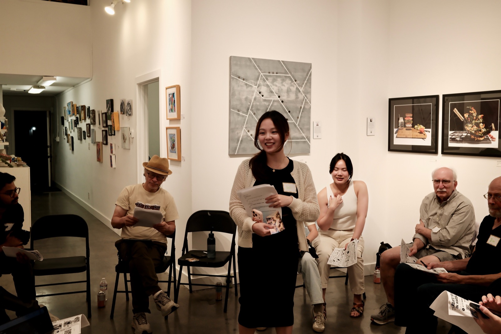 A speaker smiling and sharing with participants seated in a circle at the sixth AIC gathering.
